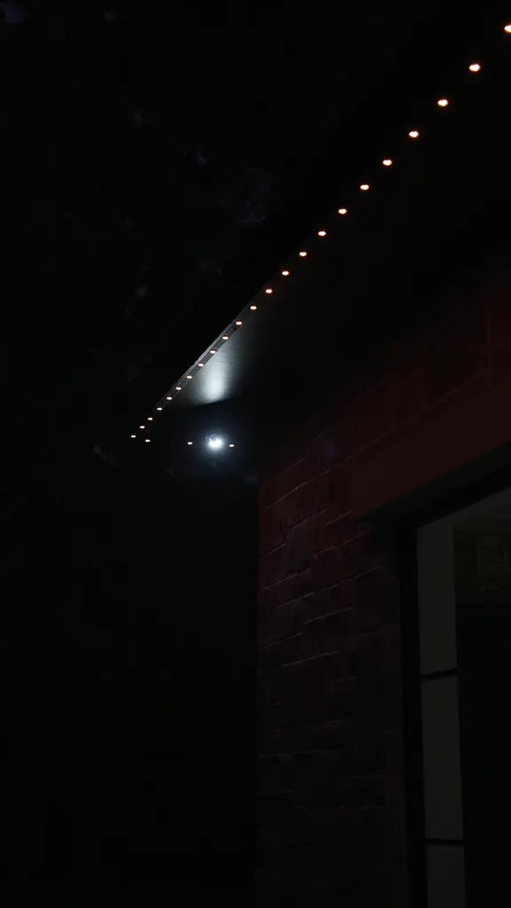 Close view of permanent LED roofline lights in warm white along a roof edge at night