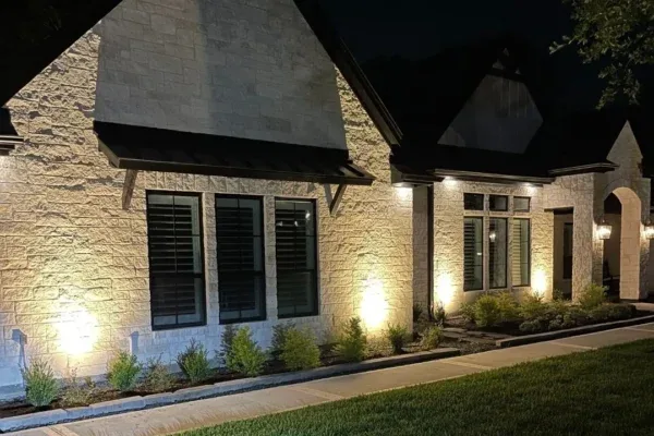 Close view of uplights on a stone home's walls at night
