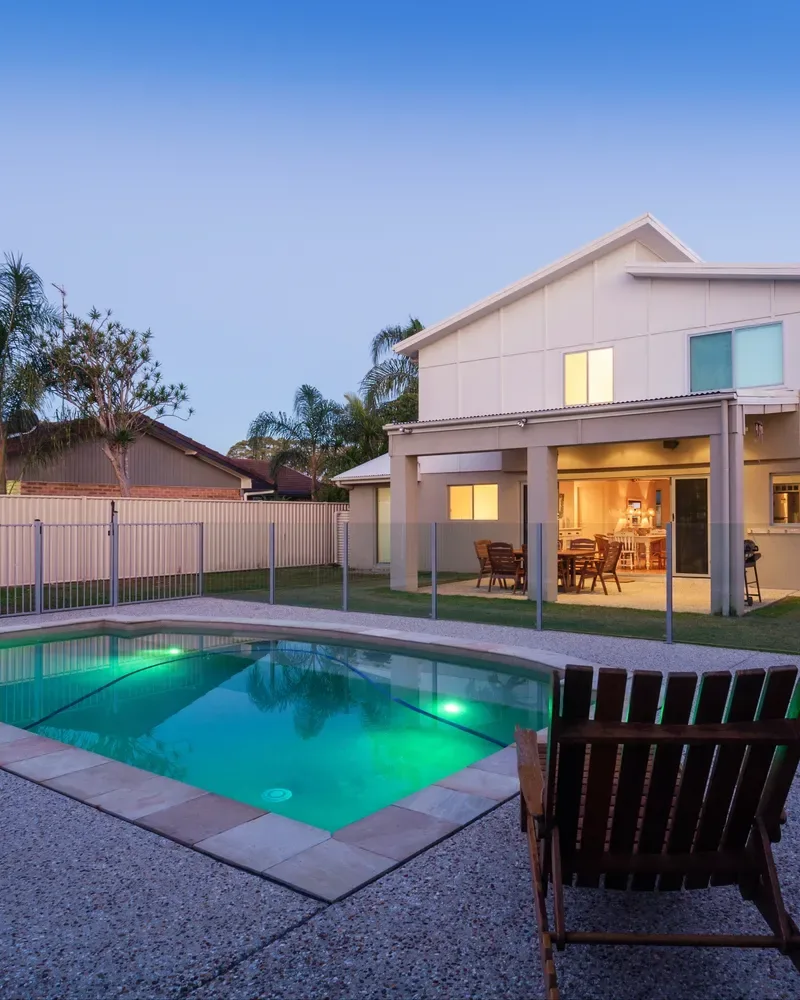 Backyard pool with green underwater LED lighting at dusk