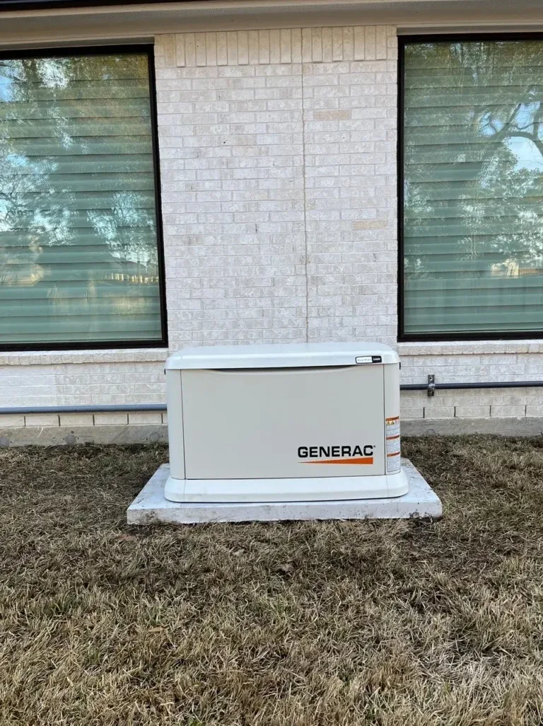 Generac standby generator on a pad against a white brick wall