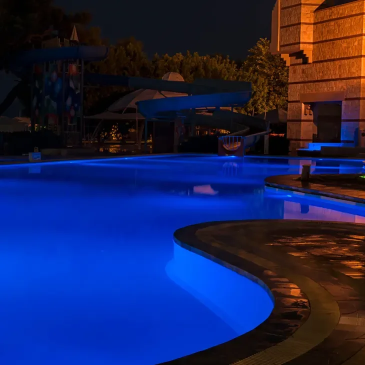 Curved swimming pool glowing blue from underwater lighting at night