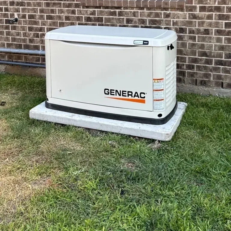 Generac Guardian standby generator on a concrete pad by a brick wall