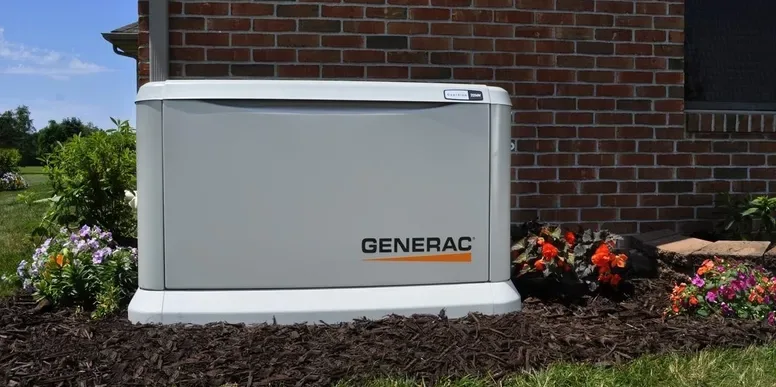 Generac standby generator beside a brick home in a flower bed