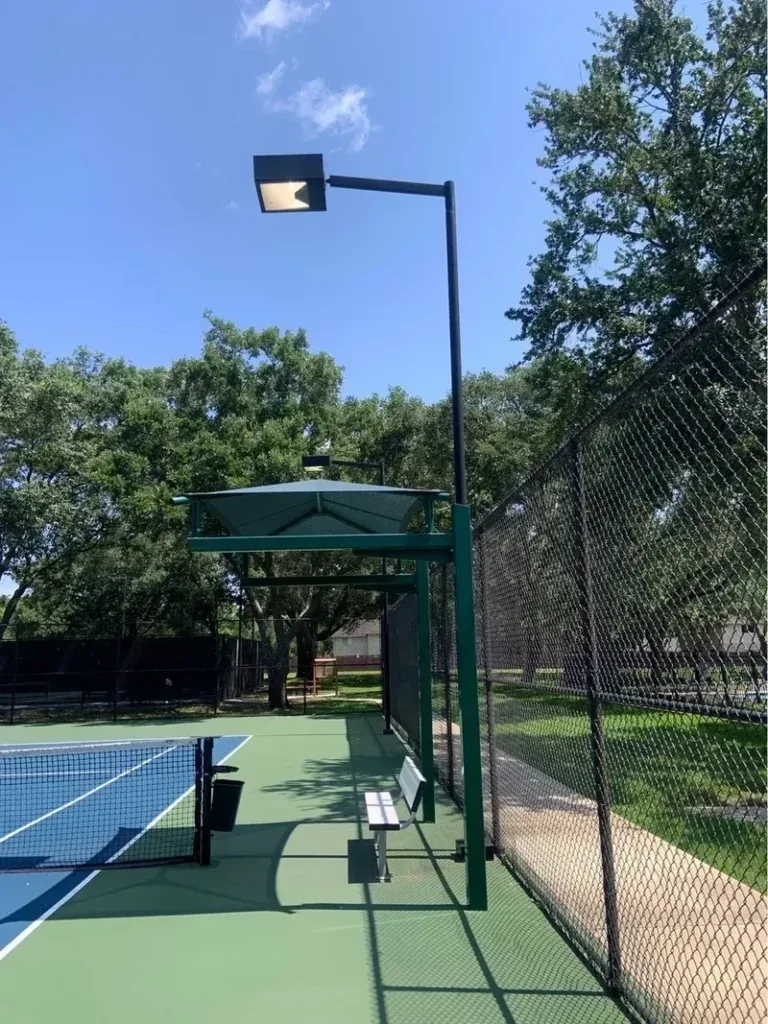 Pole-mounted floodlight above a fenced pickleball court